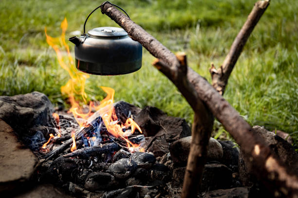 istock Making tea over an open fire in the forest. The kettle is hanging on a stick on the fire. 2166739877