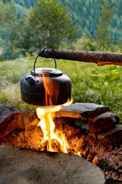 istock Making tea over an open fire in the forest. The kettle is hanging on a stick on the fire. 2166739878