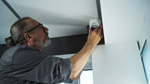 istock Professional male installer screws security camera in office room, adjusts the angle 2166744804