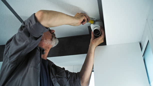 istock Professional male installer screws security camera in office room, adjusts the angle 2166744893