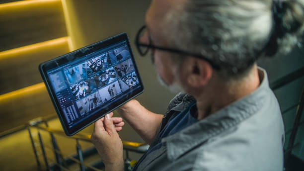 Male installer watches CCTV cameras in stylish office using tablet computer