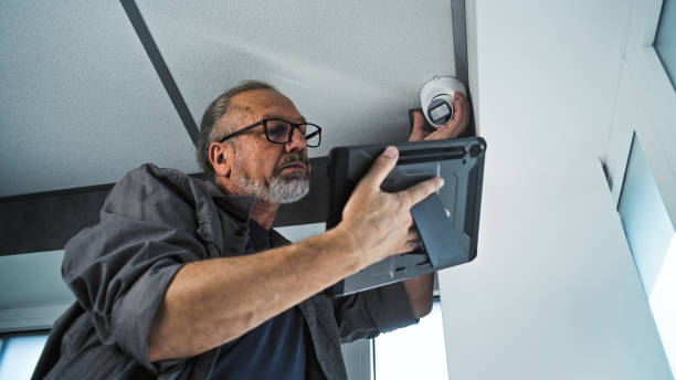 istock Male mature installer sets up CCTV camera in office room using tablet computer 2166746294
