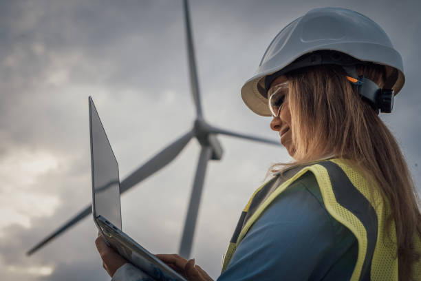 istock A focused woman utilizes a laptop at a modern wind farm, representing a committed renewable energy professional who is making important contributions and advancements to the industry 2166747755
