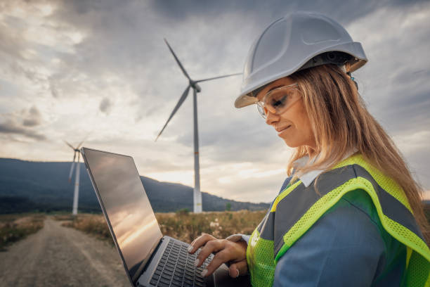 istock A dedicated Professional Engineer diligently using a laptop while situated in a picturesque wind farm, showcasing collaboration in engineering and innovation within a sustainable rural landscape 2166748119