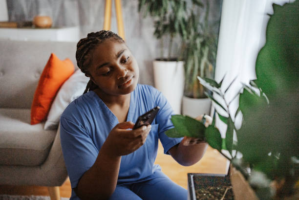 istock Nurse caring for a plant while checking her phone 2166758083