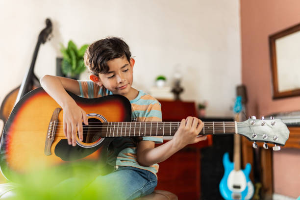 Child boy playing acoustic guitar at home