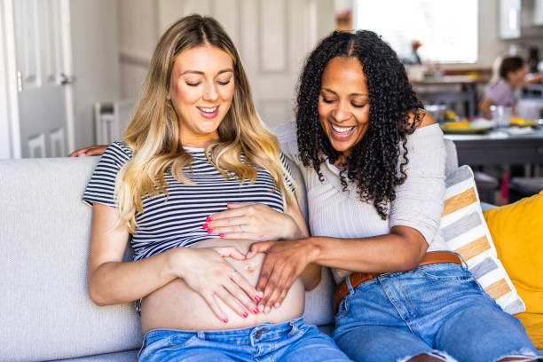 Lesbian pregnant couple talking at living home