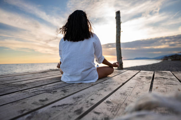 istock Woman meditating on a pier on the beach 2166768930