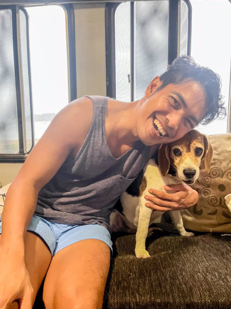 istock Man Smiling with His Dog on a Cozy Couch Inside Camper 2166770360
