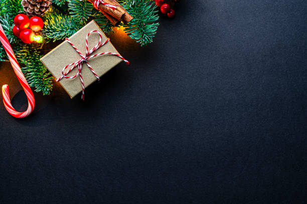 istock Christmas decor on dark background with string lights, fir tree, candy cane and gift box. Copy space 2166777127