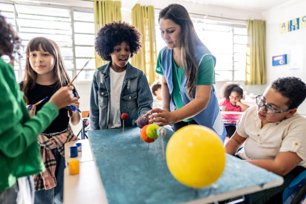 istock Teacher helping students during solar system project on classroom at school 2166778443