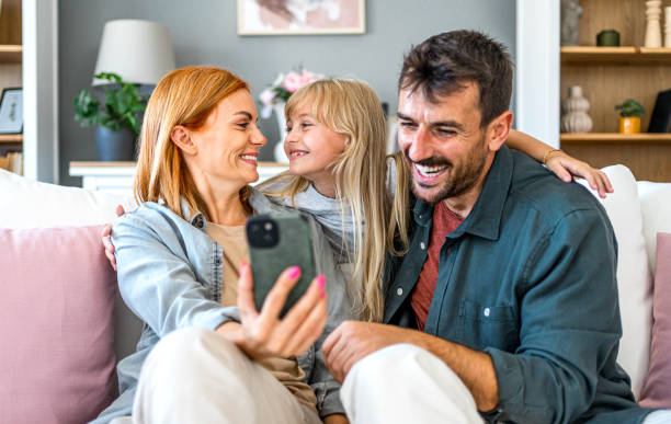 istock Family relaxing on the sofa and using phone together 2166778478