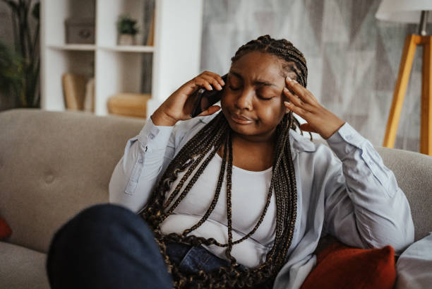istock Saddened woman on phone rubbing temples indoors 2166779969