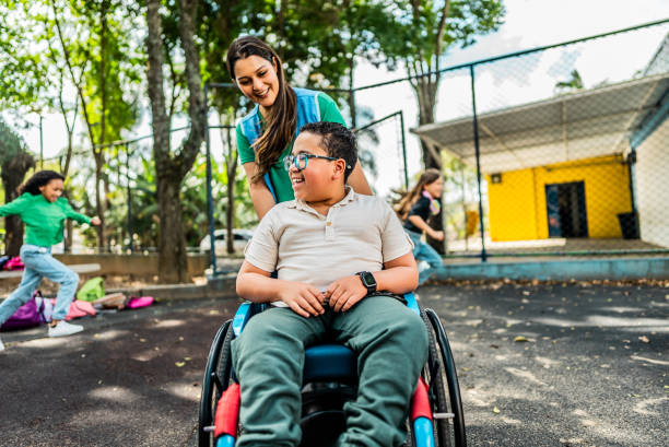 istock Teacher helping wheelchair student on schoolyard 2166780623