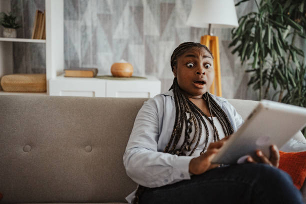 Shocked woman looking at tablet screen indoors