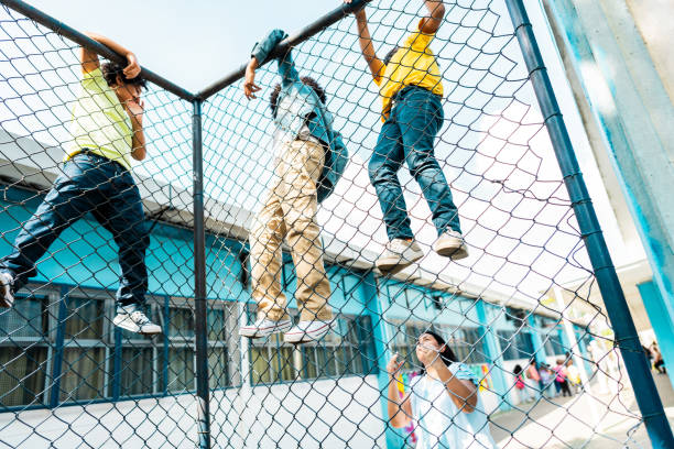 istock Teacher scolding with students climbing on chainlink fence on schoolyard 2166780911