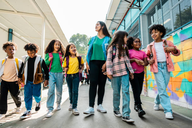 istock Teacher and students walking holding hands on schoolyard 2166781096