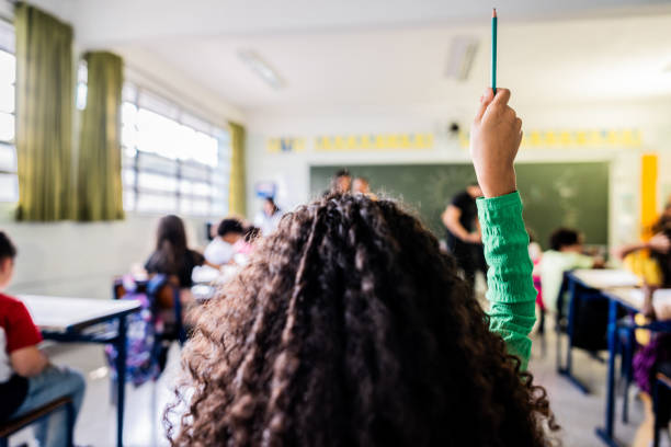 Rear view of a student asking on classroom at school