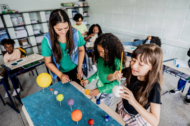 istock Teacher helping students during solar system project on classroom at school 2166782224