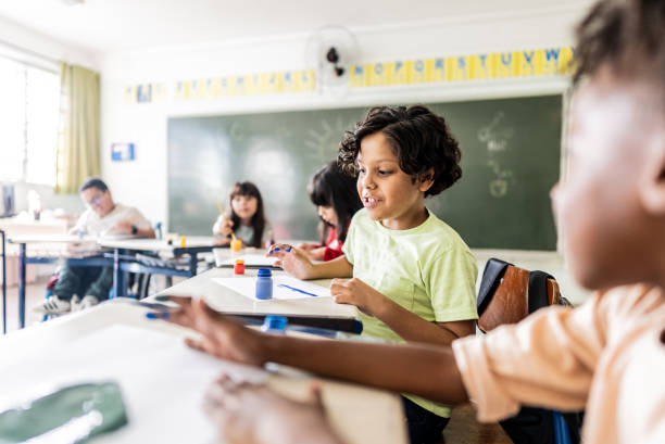 istock Schoolboy talking with friend on classroom at school 2166782824