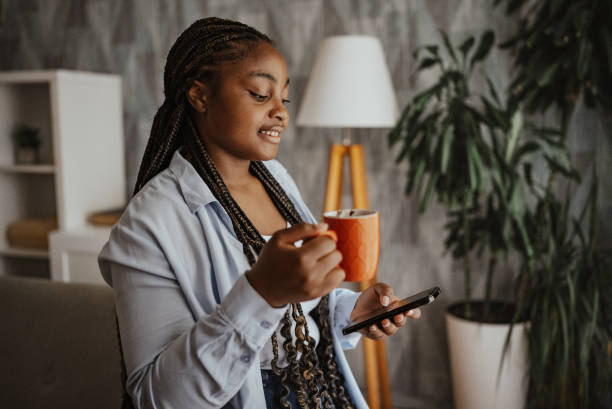 istock Smiling woman with orange coffee mug using smartphone 2166783524