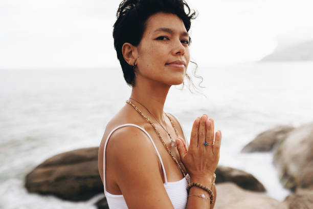 istock Woman in prayer pose looking serene at the beach during vacation 2166785322