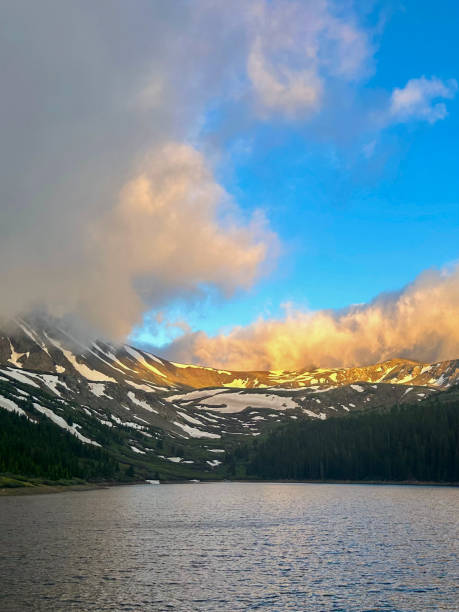 Clouds And Mountains Reflect The Sunrise  Under An Alpine Lake