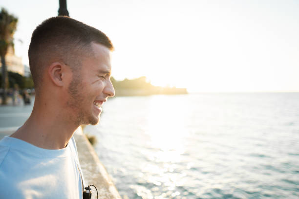 istock Young man enjoying sunset while walking near the sea 2166794404