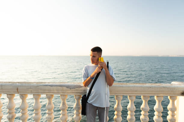 Blind person using smartphone app for orientation and accessibility at seafront