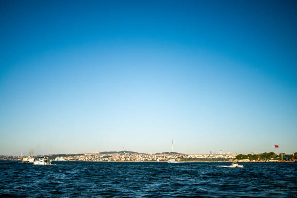 A picturesque view of the Bosphorus in Istanbul, featuring a passenger ferry cruising through the water, with the city's skyline and iconic landmarks in the background.
