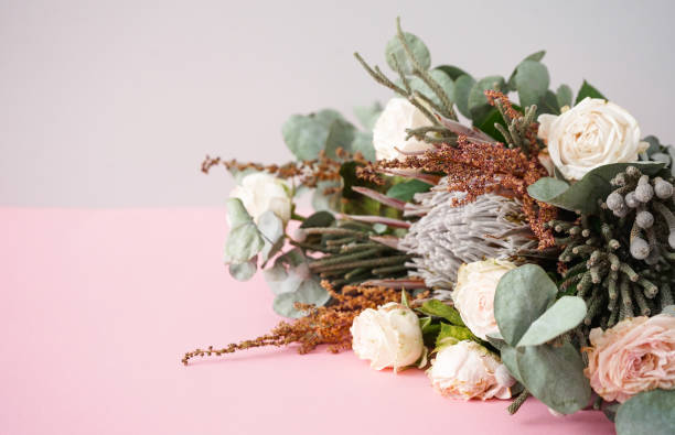 istock Beautiful bouquet with white roses, protea and brunia branches on a pink background. 2166800899