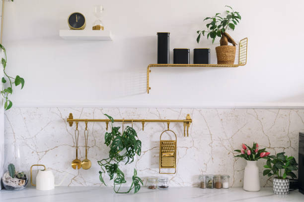 Modern kitchen interior featuring marble countertop, golden accents, and plants in a bright, minimalist space