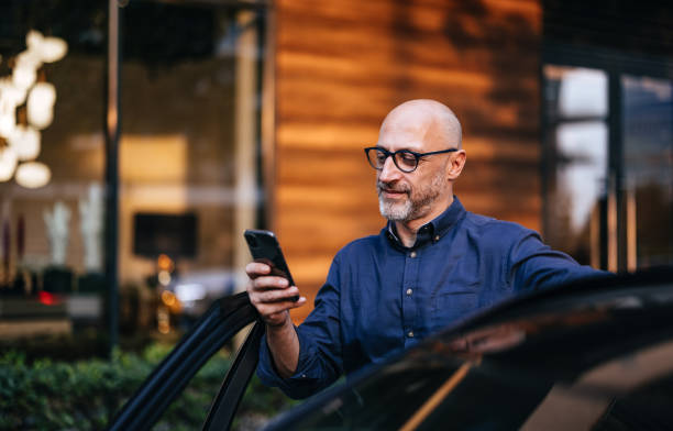 istock Businessman Using Smartphone While Entering Car in Urban Setting 2166802691