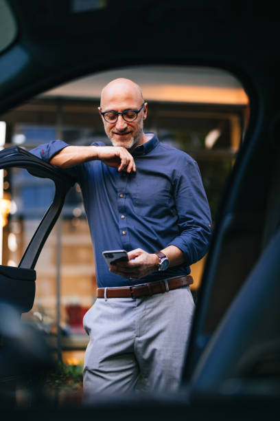 istock Businessman Relaxing Next to Car Using Smartphone in Urban Setting 2166802698