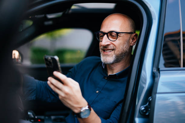 istock Businessman Smiling and Using Smartphone in Car 2166802709