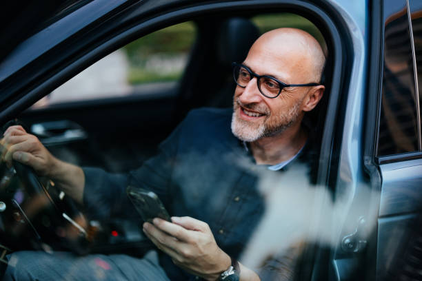 istock Smiling Businessman Using Smartphone While Sitting in Car 2166802716