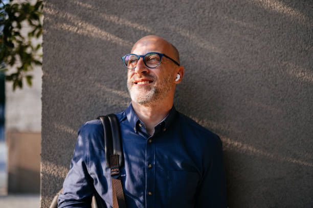 istock Confident Businessman Smiling Outdoors with Earbuds and Glasses 2166802735