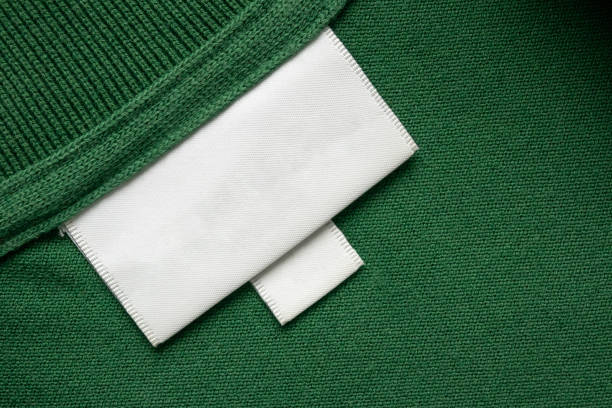 istock Blank white laundry care clothes label on green shirt fabric texture background 2166810240