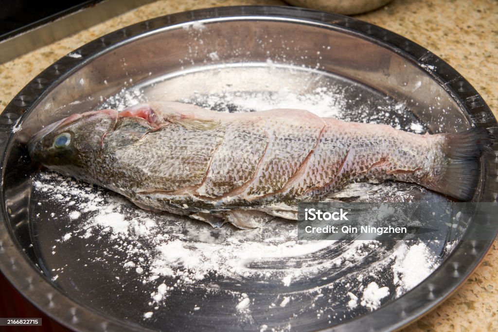 Ein Koch in der Küche bereitet gebratenen Fisch zu und brät einen ganzen Fisch - Lizenzfrei Graskarpfen Stock-Foto Ein Koch in der Küche bereitet gebratenen Fisch zu und brät einen ganzen Fisch - Lizenzfrei Graskarpfen Stock-Foto