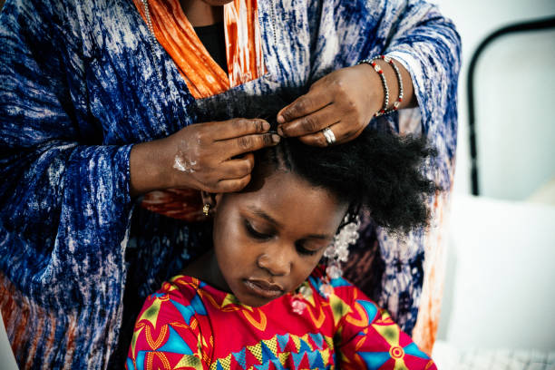 African mother doing her daughter's hair before to school in the bedroom at home