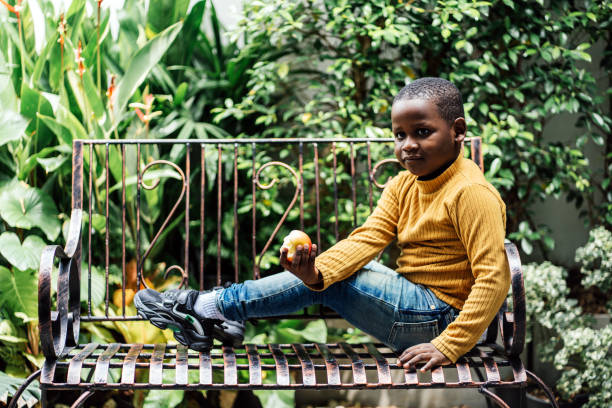 Cheerful black boy eating red apple at home