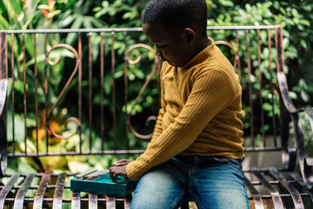 Close up of Black boy playing Kalimba in backyard