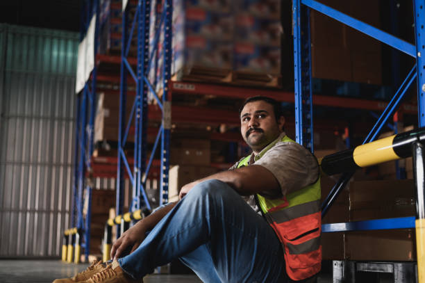 istock Tiredness from hard work concept. Warehouse worker laying on the floor in warehouse after tiring work. 2166825333