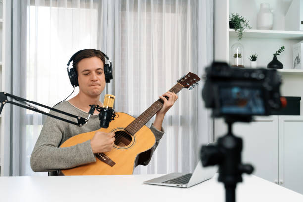 istock Smart singer recording by camera, playing guitar along singing. Pecuniary. 2166830191