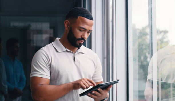 istock Office, planning and man with tablet by window for network,  review and communication to client. Stocks, trader and investor with technology by glass for market research, feedback and digital insight 2166832947