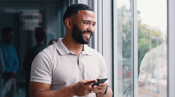 istock Office, thinking and man with phone by window for network,  contact and communication to client. Happy, worker and technology with idea at creative agency for research, feedback and project planning 2166832948