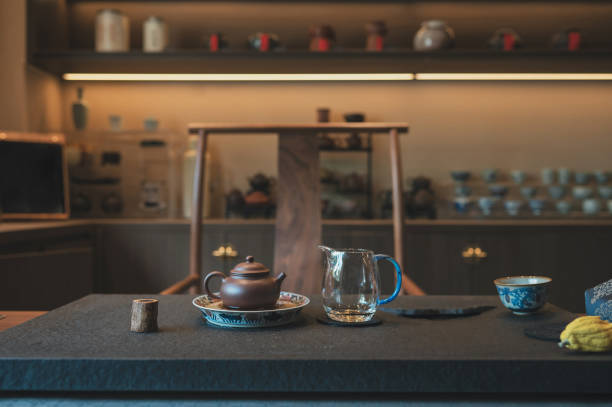 An elegant Chinese tea ceremony setup featuring a traditional teapot, a glass pitcher, and a cup, all beautifully arranged on a minimalist table with a dark mat, symbolizing the intricate art and culture of Japanese tea ceremonies.