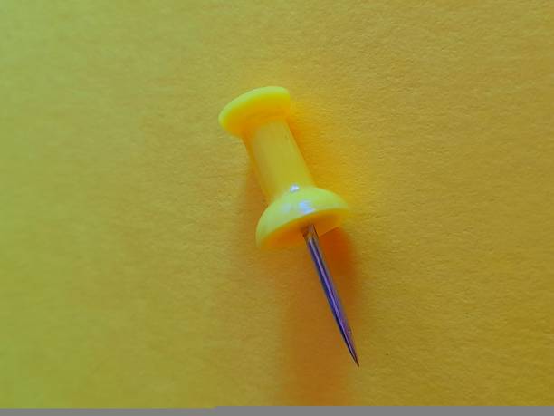 istock One yellow paper clip pin with yellow background 2166839697