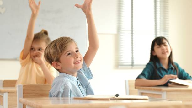 istock Smart caucasian boy raising hand for asking teacher at classroom. Pedagogy. 2166840833