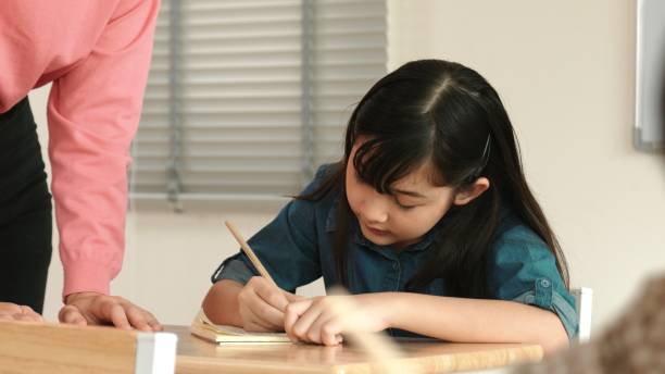 istock Asian girl writing or taking a note while teacher checking classwork. Pedagogy. 2166840980
